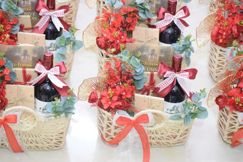 Bottle-led woven basket with red florals and a statement bow
